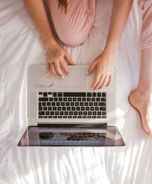 Woman sitting on bed using a laptop